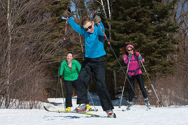 Photo of three women enjoying cross country skiing on a beautiful winter day.